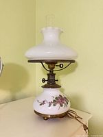 Full view of lamp showing shade, chimney, painted font, metal hardware and cord