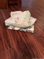 Two folded quilts stacked on floor