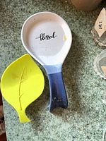 Both spoon rests visible: ceramic with text and silicone leaf design