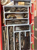 Drawer showing assorted drill bits, taps, hole saws and accessories in trays