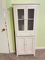 Front view of the tall off-white storage cabinet showing overall form and finish