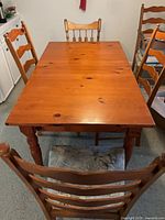 Top view of solid pine dining table with four ladder-back chairs visible