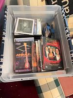 Top view of bin showing mixed DVDs, CDs, VHS tapes