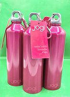 Front view of three metallic pink Jogi bottles grouped together