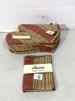 Stack of striped oven mitts beside folded table linens pack