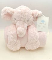 Front view of pink elephant plush attached to rolled pink blanket with retail tag