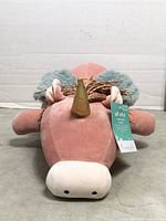 Front view of pink Pegasus weighted plush pillow with gold horn, hang tag visible