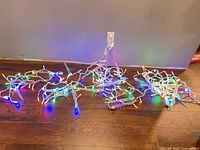 Three tangled strands of multicolor LED icicle lights illuminated on floor