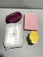 All four Tupperware pieces grouped: purple breakfast maker, pink rectangular container, white sealed container, yellow sugar container