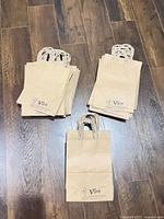 Three stacks of kraft paper gift bags each with twisted handles