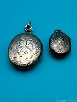 Front view of both lockets showing engraved designs and size difference