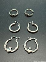 All three pairs of sterling silver hoop earrings displayed flat
