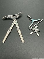 Ski brooch and curling pendant front view