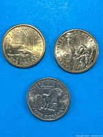 All three $1 coins displayed obverse up on blue background