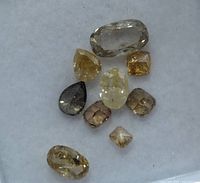 Group of nine faceted fancy color diamonds on white pad