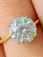 Ring on finger showing round lab diamond and yellow gold band