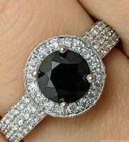 Close-up of ring showing black diamond, CZ halo, pavé band