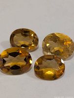 Four oval yellow citrine gemstones on white background