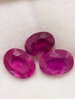 Three oval faceted rubies on display pad