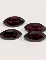 Four marquise faceted garnet stones on white background