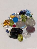 group of assorted coloured loose gemstones on white background