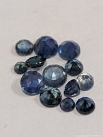 Group of fourteen loose round blue sapphires on white background