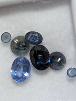 Top view of seven loose sapphires on white pad