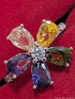 Top view of ring showing six colored pear-cut sapphires and central clear stone