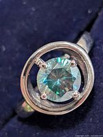 Front view of silver ring with blue-green moissanite