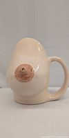 Front view of breast-shaped mug showing nipple spout and handle
