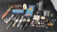 Overview of entire lot displaying watches, pins, cufflinks, harmonica, knife, stein, lighters, coins and keychains