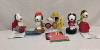 Line-up of all five Snoopy keychain figures with instruction sheets