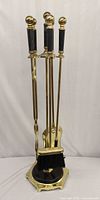 Full view of assembled brass fireplace tool set on stand