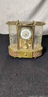 Front view of brass mantel clock showing dial and base drawer