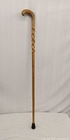 Full view of wooden walking cane with rubber tip