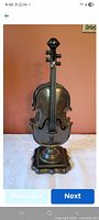 Front view of bronze color violin sculpture on base