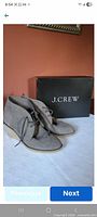 Side view of grey suede wedge boots with laces next to J.Crew shoe box