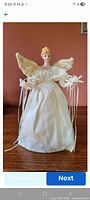 Front view of angel tree topper showing gown, wings, porcelain head