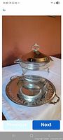Chafing dish with lid on stand and separate serving platter in foreground