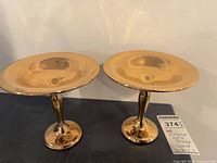 Pair of gold plated pedestal stands side by side