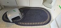 Large and small braided rugs with stool placed on top