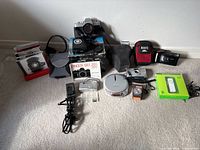 Group shot of all cameras, audio devices, iPod, games and accessories laid on carpet