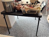 Full view of black folding card table with items on top