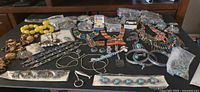 Full lot on table showing various necklaces, bracelets, rings, earrings and bagged items