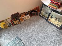 Group of two horse prints and multiple empty frames on floor