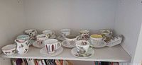 Full shelf view showing 11 teacup and saucer sets, fingertip tray to right