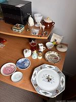 Overall lot showing plates, tins, figurines on desk