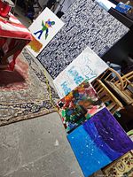 Five canvases leaning against furniture and wall showing sizes and artwork