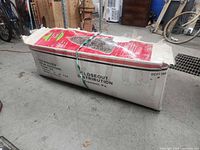 Cardboard box containing artificial Christmas tree, shows vendor marking and overall box wear