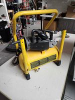 Front view of yellow portable air compressor showing tank, motor, carry handle, and power cord